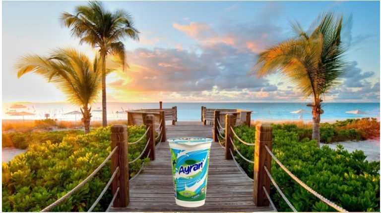 Uyumsuzluklar dersindeki ayran göndermesi: tropik sahil fotoğrafına eklenmiş ayran bardağı.